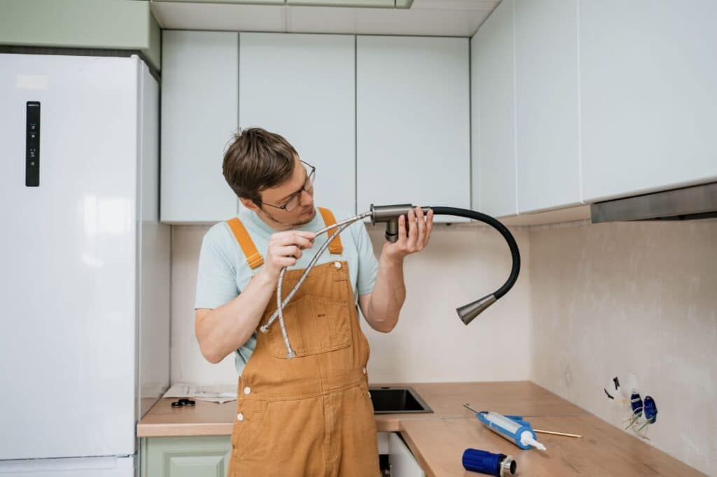 a man in overalls holding a faucet